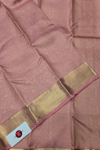 Close-up of a pink saree with a gold border and a visible brand label.