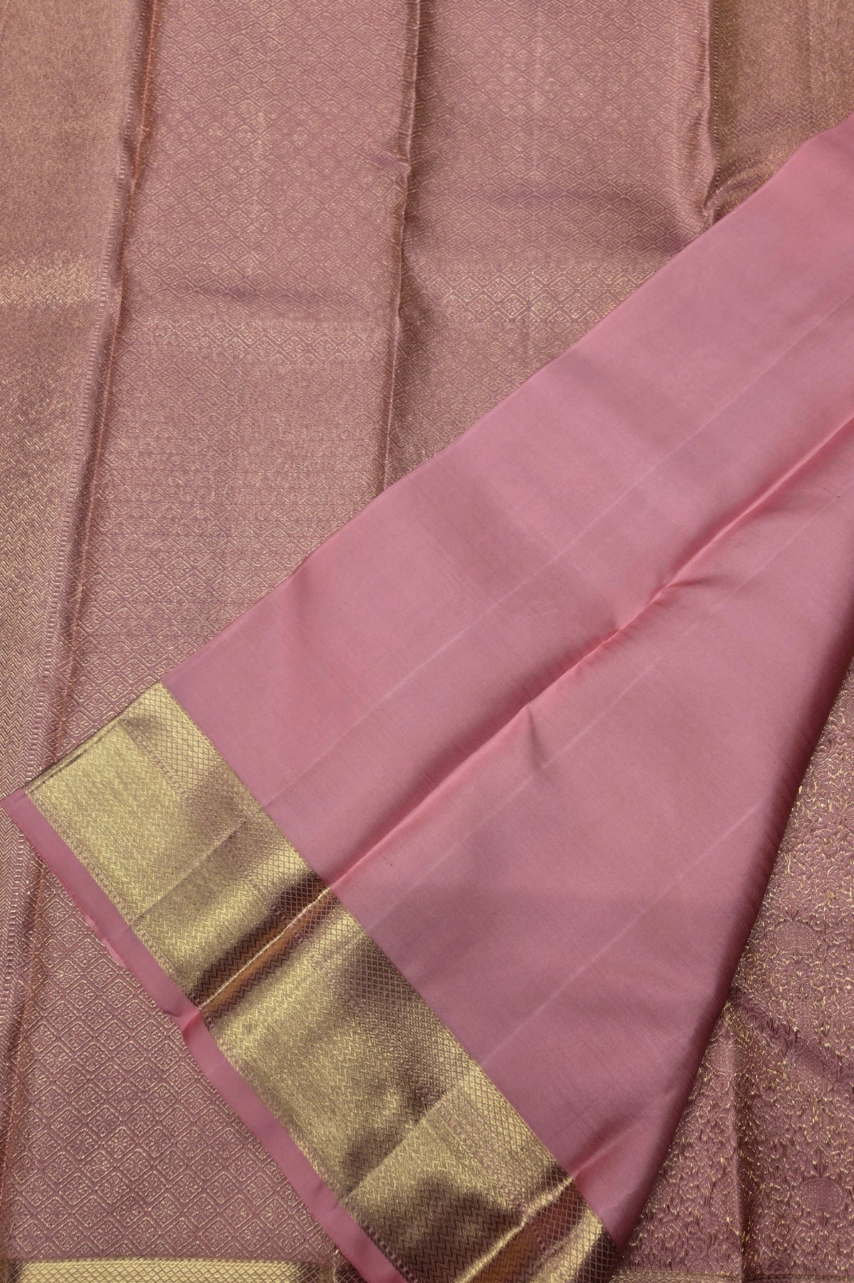 Pink saree with a gold border on a textured brown background