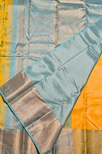 Close-up of a traditional saree with a yellow and blue pattern.