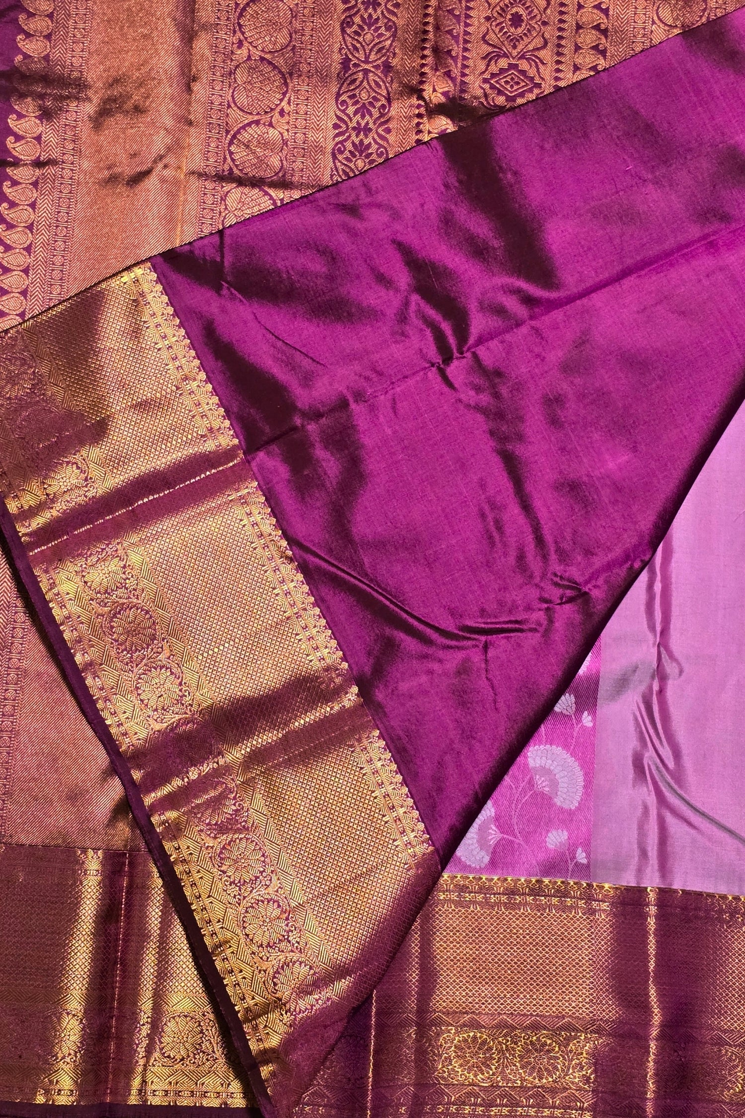 Purple saree with gold border on a textured fabric background