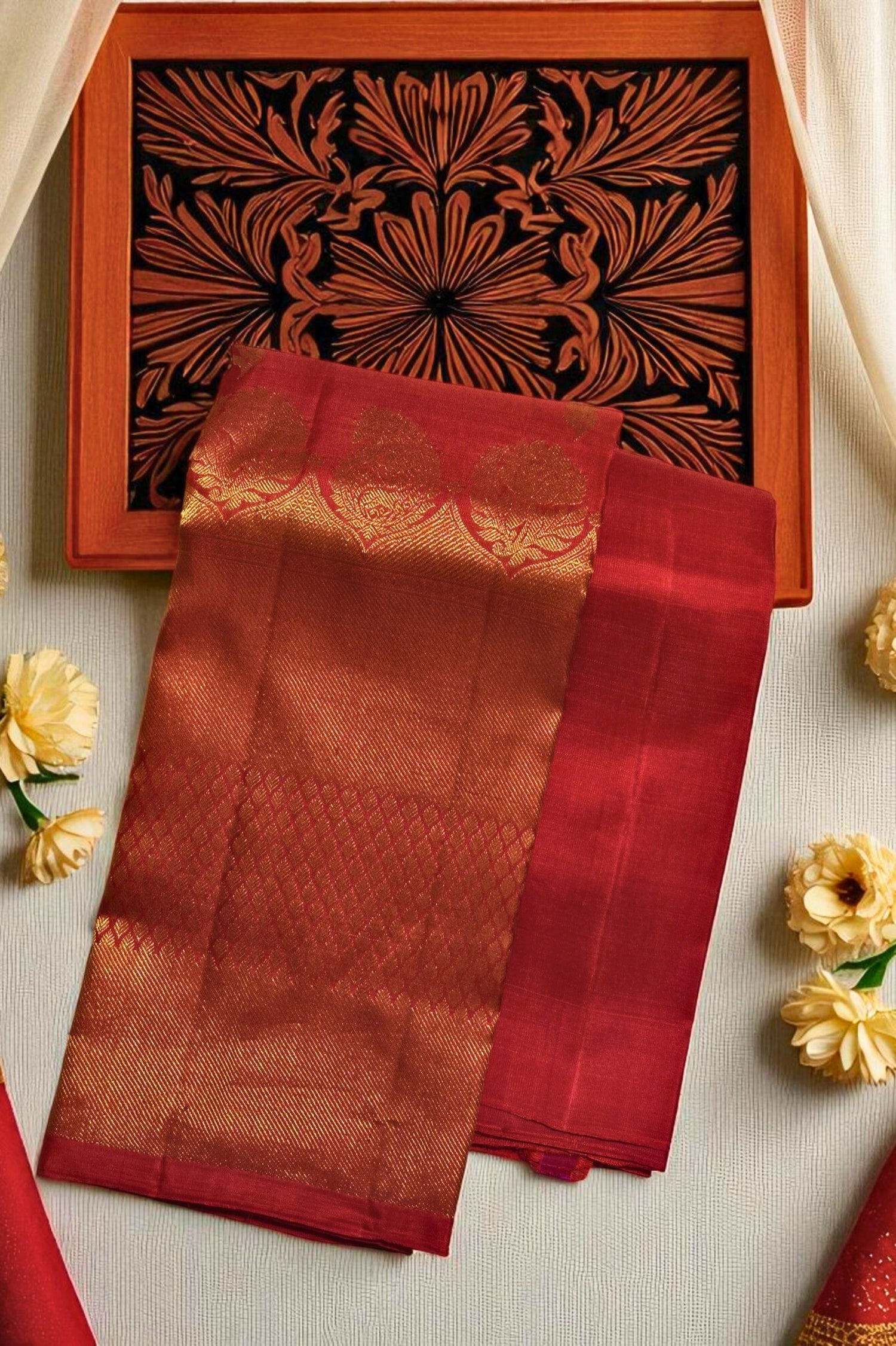 Red saree with gold border on a decorative wooden box with floral design