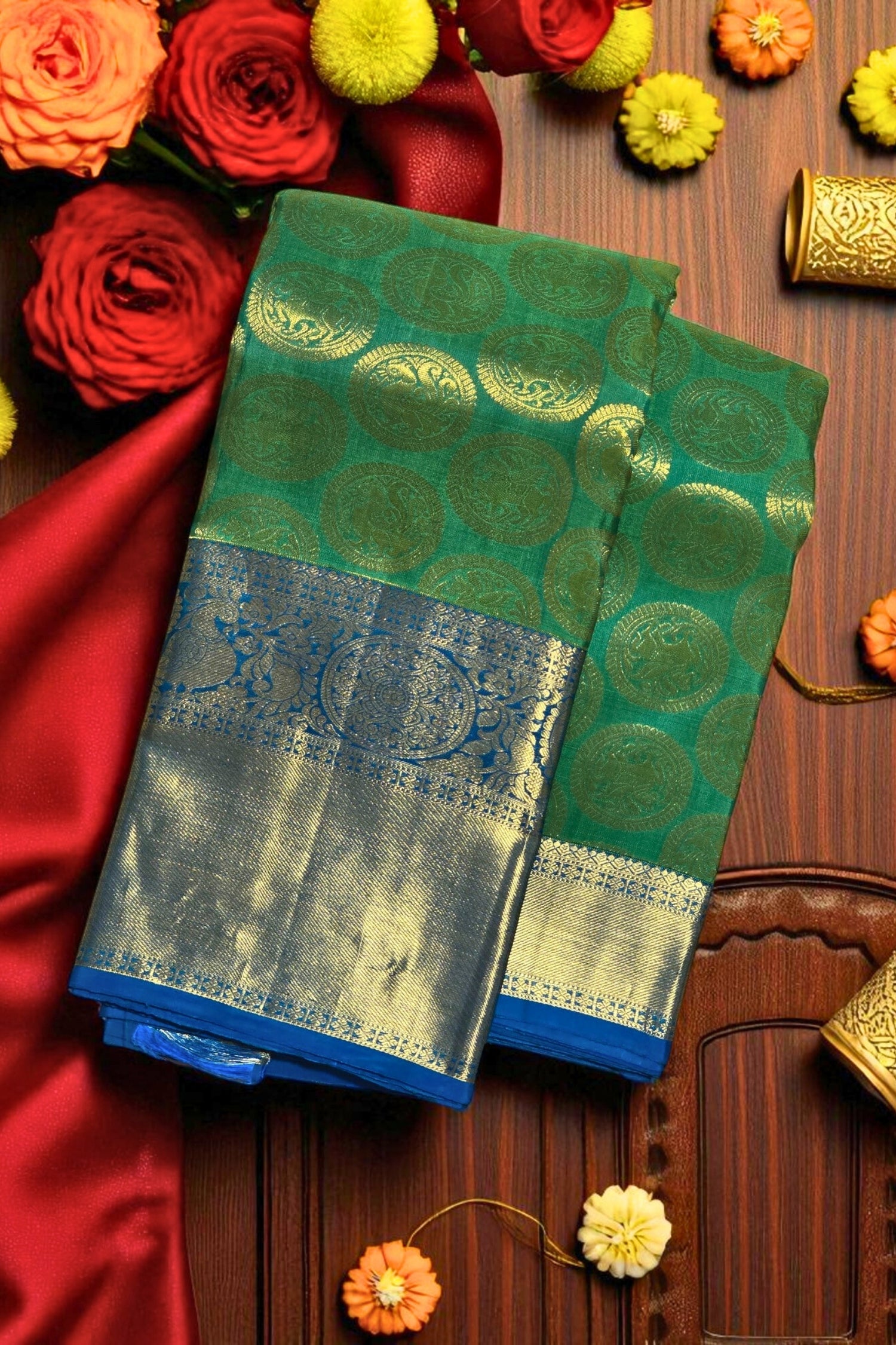Green and blue saree with floral decorations on a wooden surface