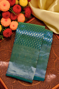 Green fabric with intricate patterns on a textured surface with flowers in the background