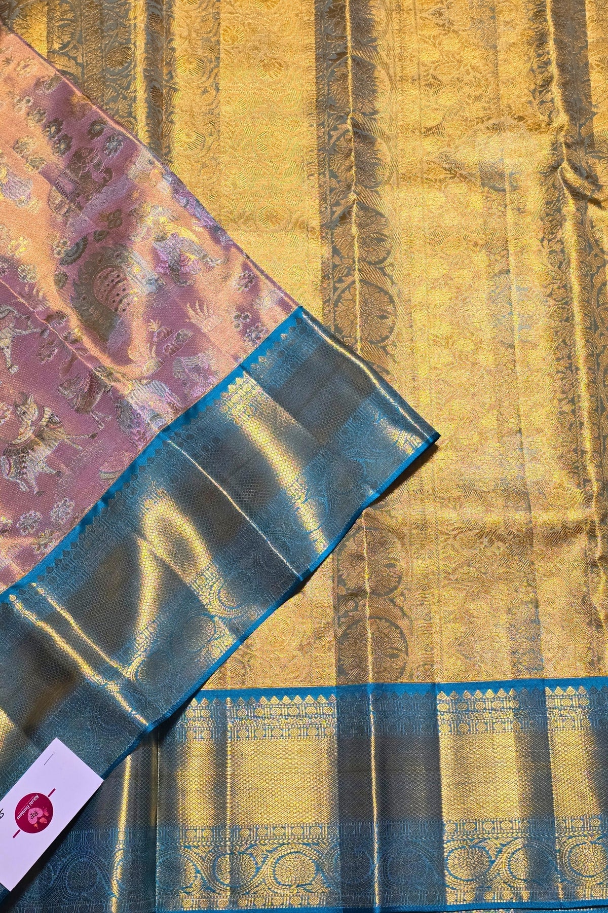 Gold saree with blue border and intricate patterns on a textured background