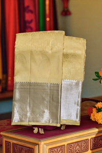 Beige saree with silver border on a wooden table with decorative elements