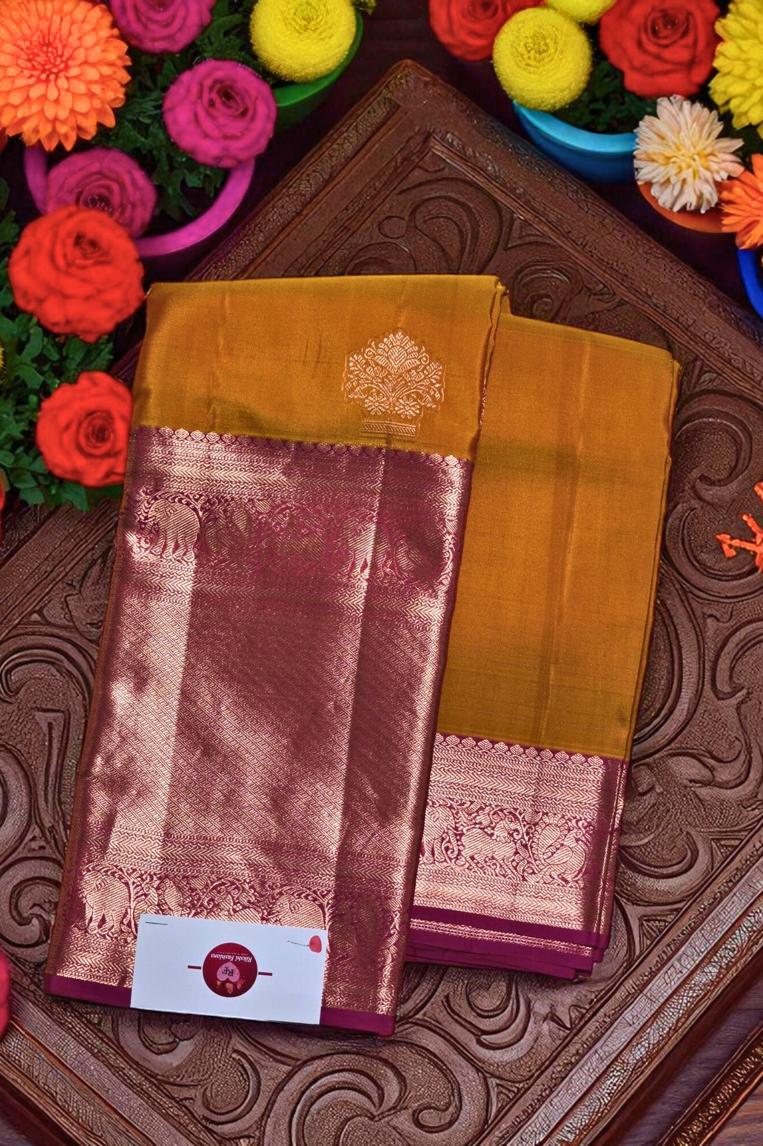 Yellow saree with pink border on a decorative background with flowers