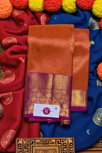 Brown saree with purple border on a colorful fabric background