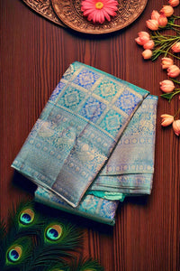 Folded fabric with intricate patterns on a wooden surface with flowers and peacock feathers.