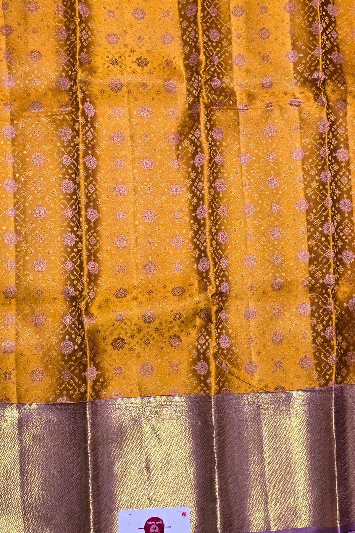 Yellow fabric with brown patterns and a visible brand label.