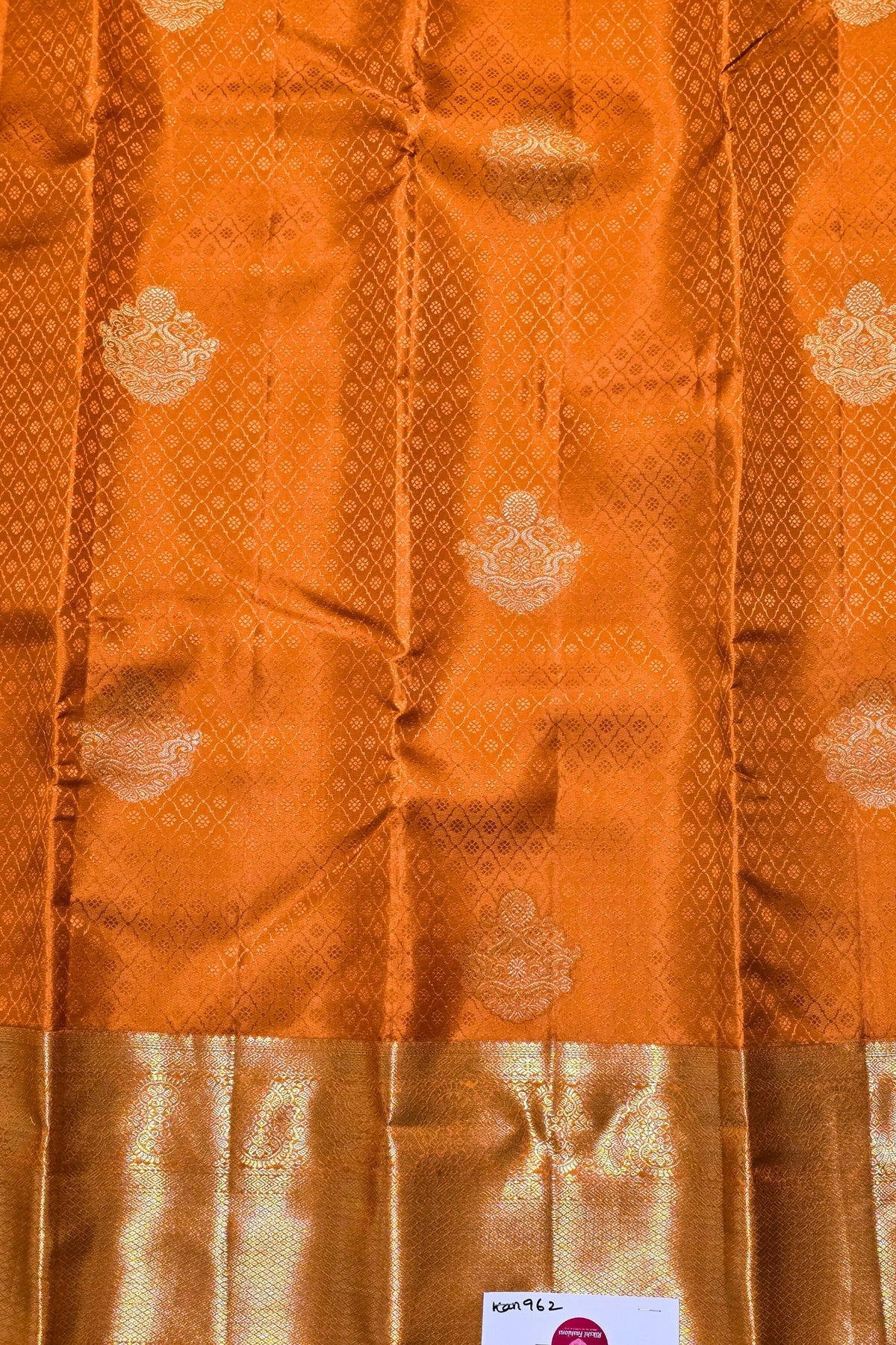 Orange fabric with gold patterns and a visible brand label.