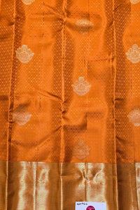 Orange fabric with gold patterns and a visible brand label.