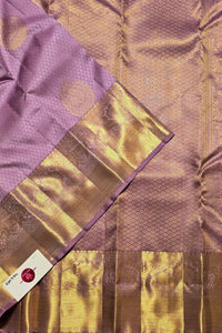 Close-up of a fabric with gold and purple patterns, featuring a brand label.