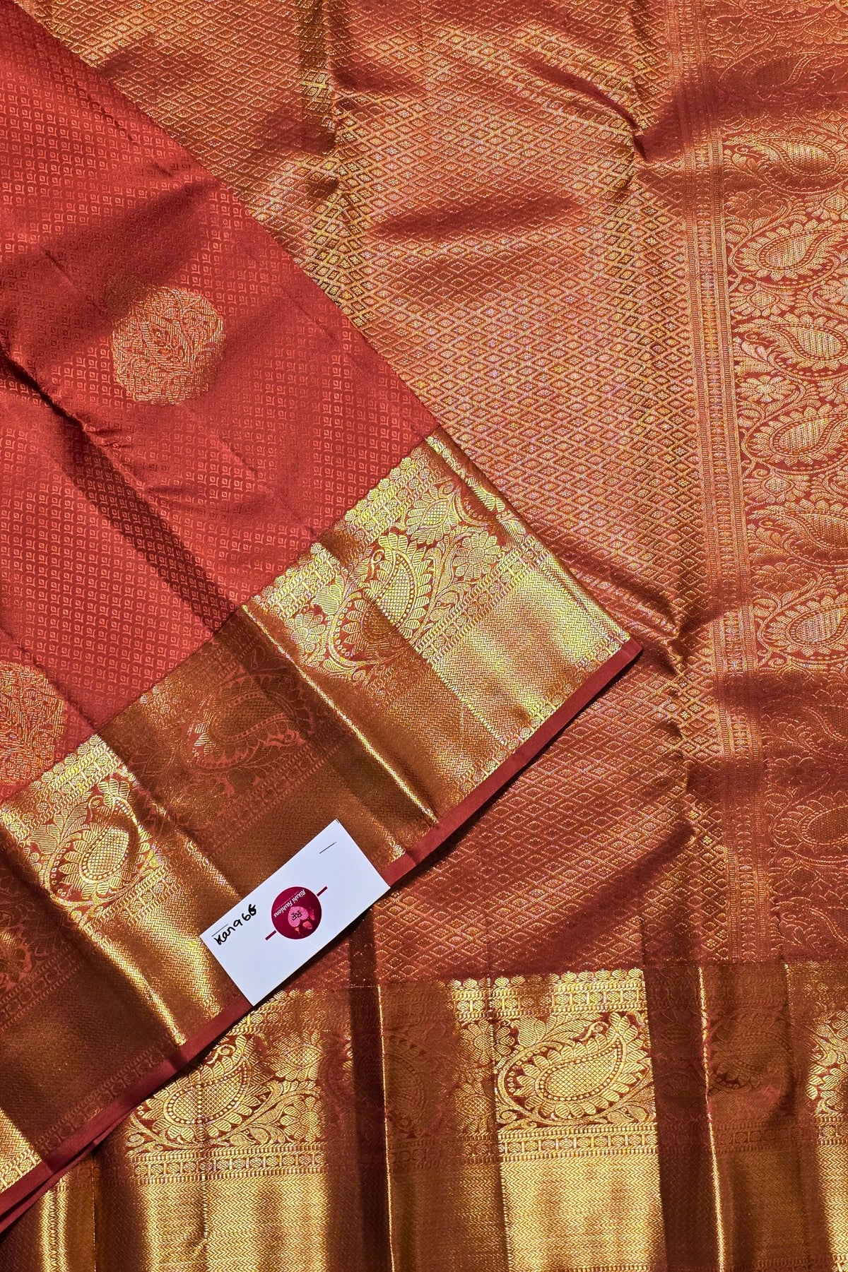 Brown and red saree with intricate patterns and a visible brand label.