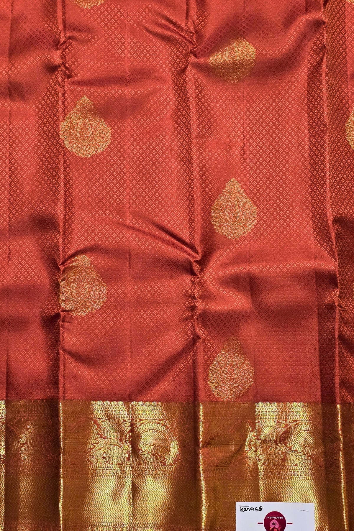 Red fabric with gold patterns and a brand label in the corner