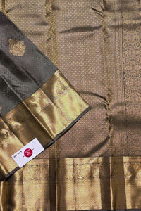 Close-up of a traditional fabric with gold and black patterns, featuring a brand label.