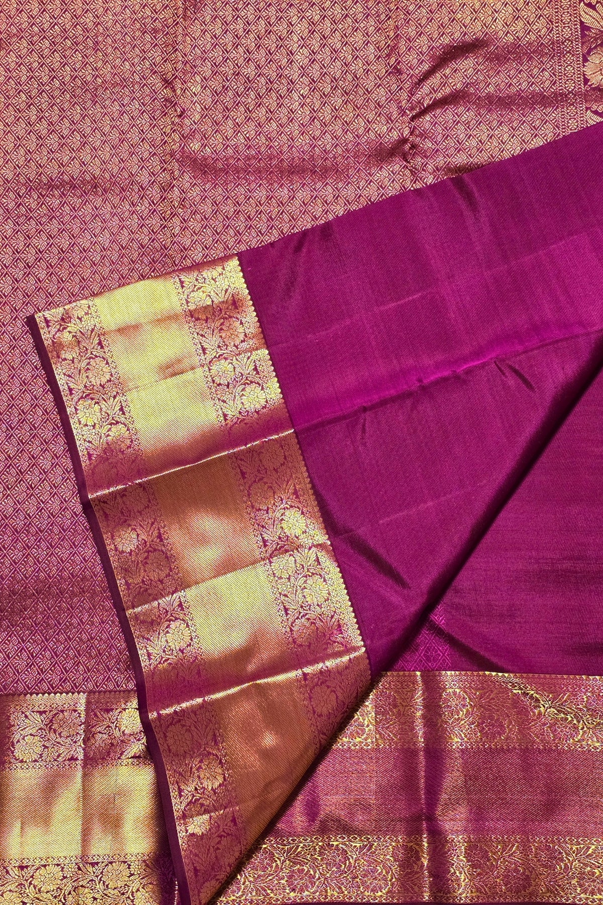 Purple saree with gold border on a matching fabric background