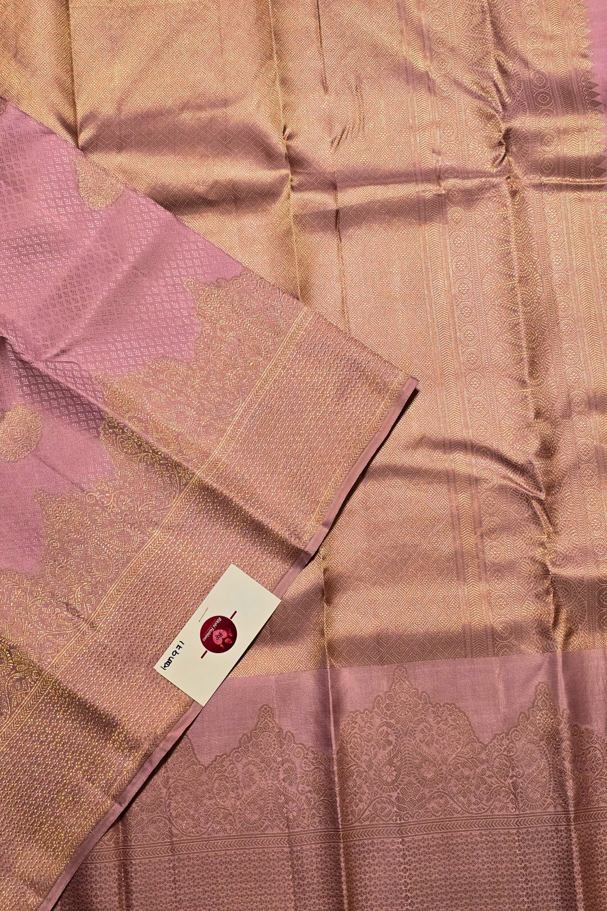 Pink saree with a woven pattern and a visible brand label.