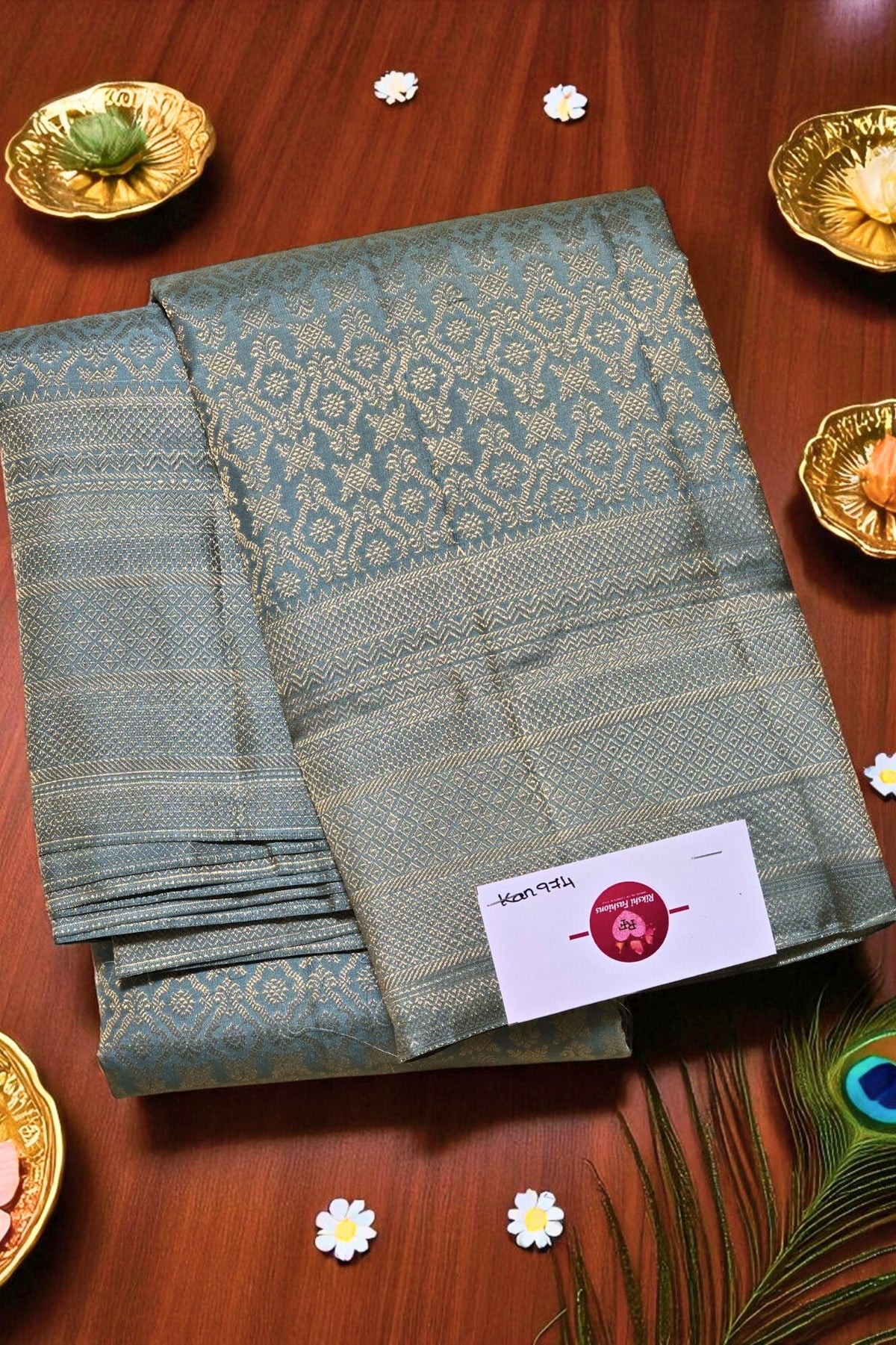 Green saree with a brand label on a wooden surface with decorative items.