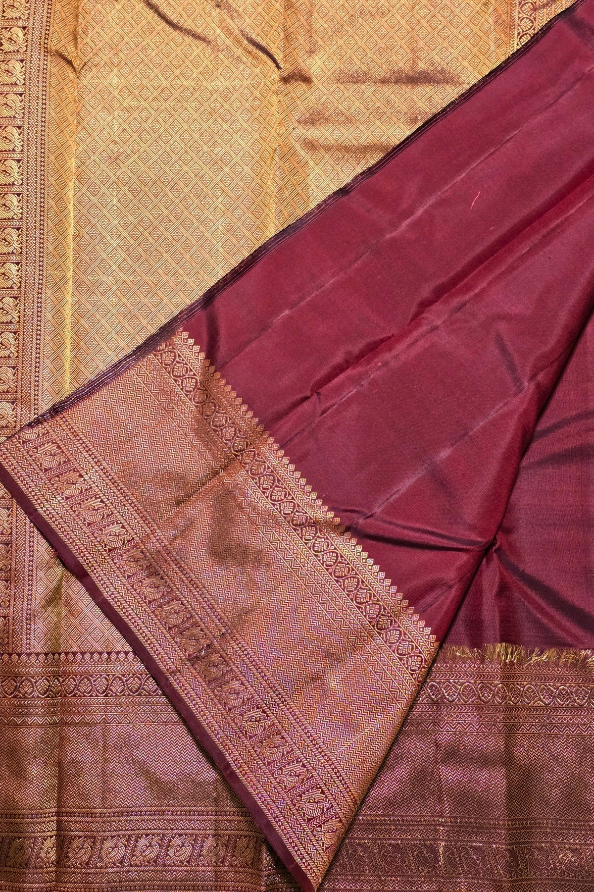 Maroon saree with gold border on a textured fabric background