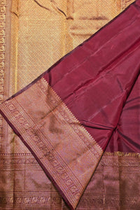 Maroon saree with gold border on a textured fabric background