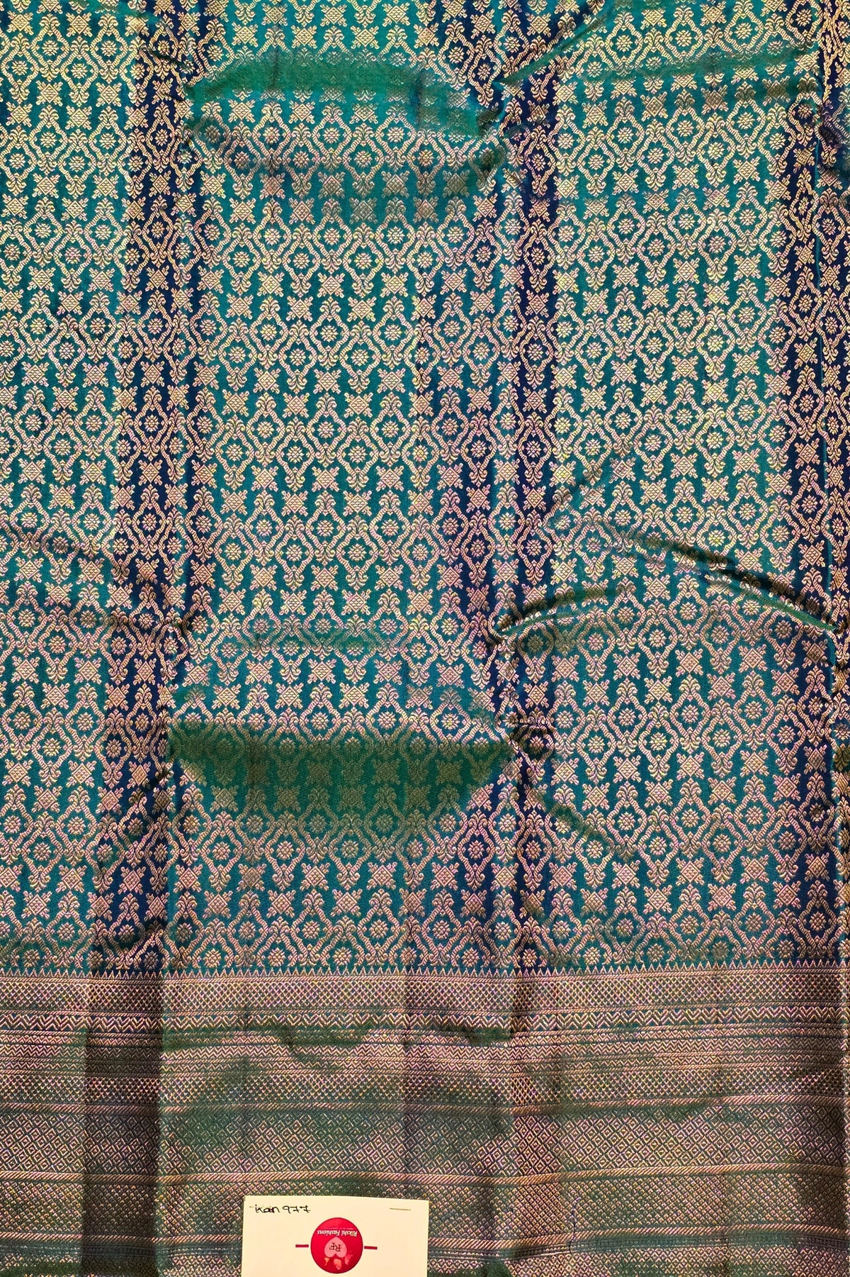 Textile with intricate green and blue pattern on a plain background