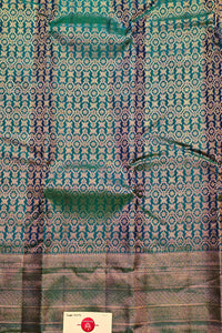 Textile with intricate green and blue pattern on a plain background