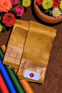 Gold saree with a brand label on a patterned surface with flowers and colorful fabrics.
