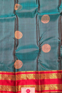 Teal fabric with gold circular patterns and a red border