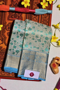 Teal and beige saree with floral patterns on a decorative background