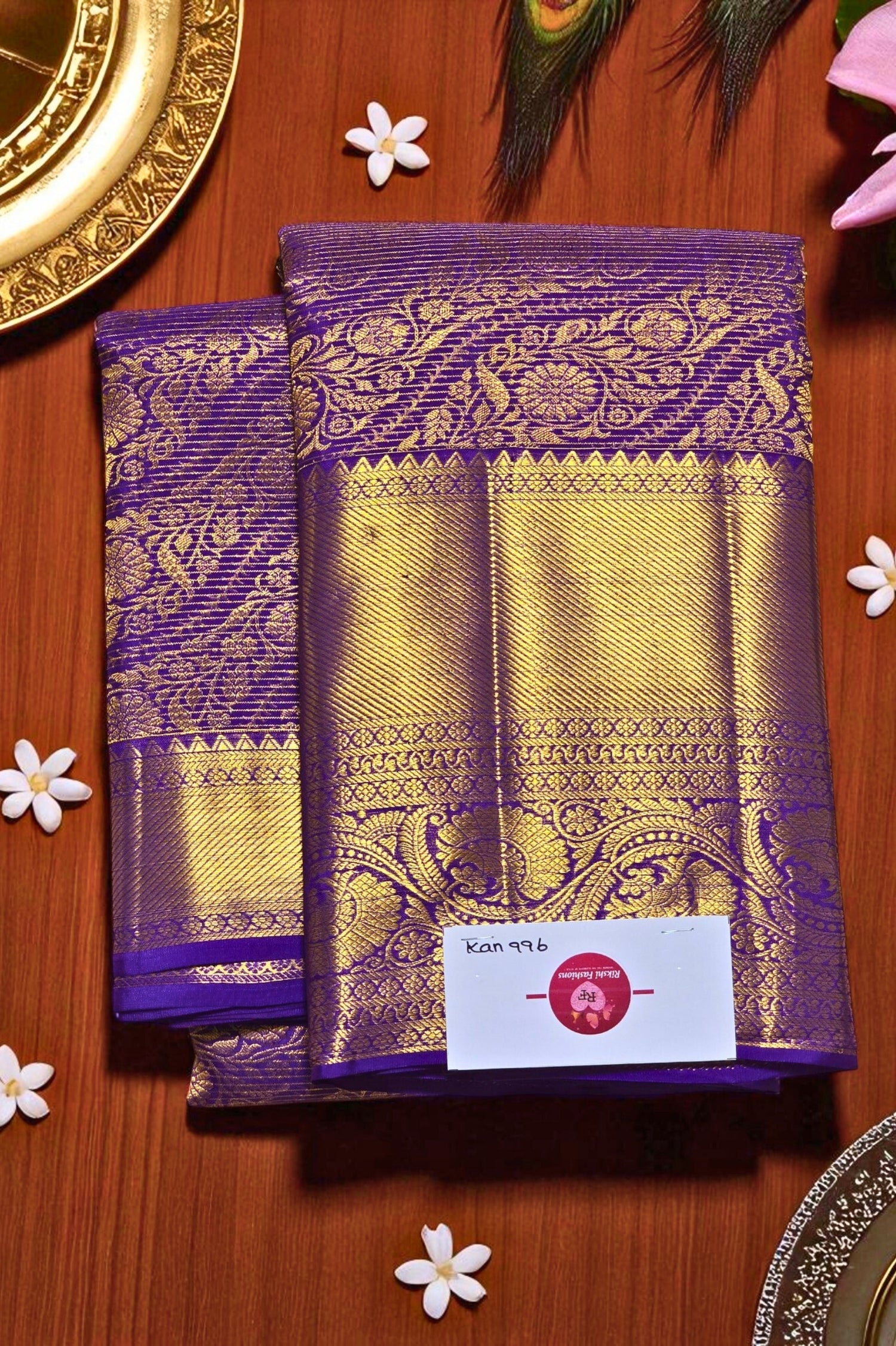 Purple and gold saree with a brand label on a wooden surface