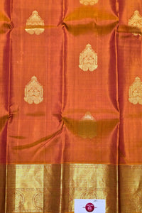 Orange fabric with gold patterns and a visible brand label.