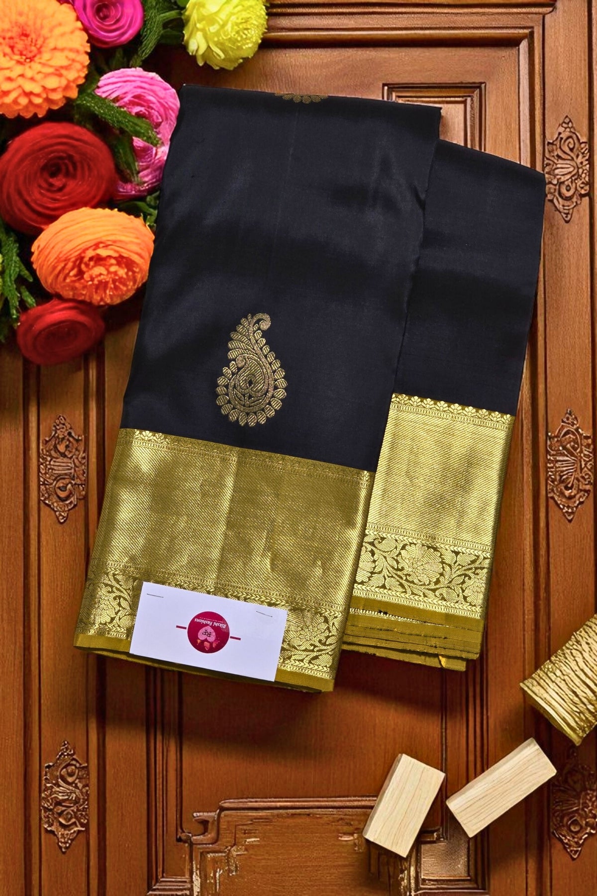 Black saree with gold border on a wooden background with flowers