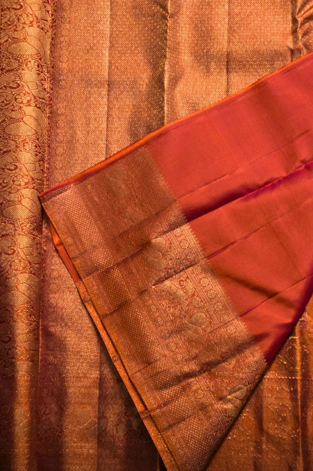 Close-up of a red and gold saree with intricate patterns.