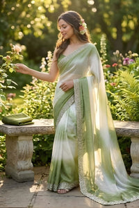 Woman in a green and white saree standing in a garden