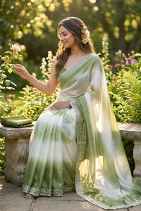 Woman in a green saree sitting in a garden