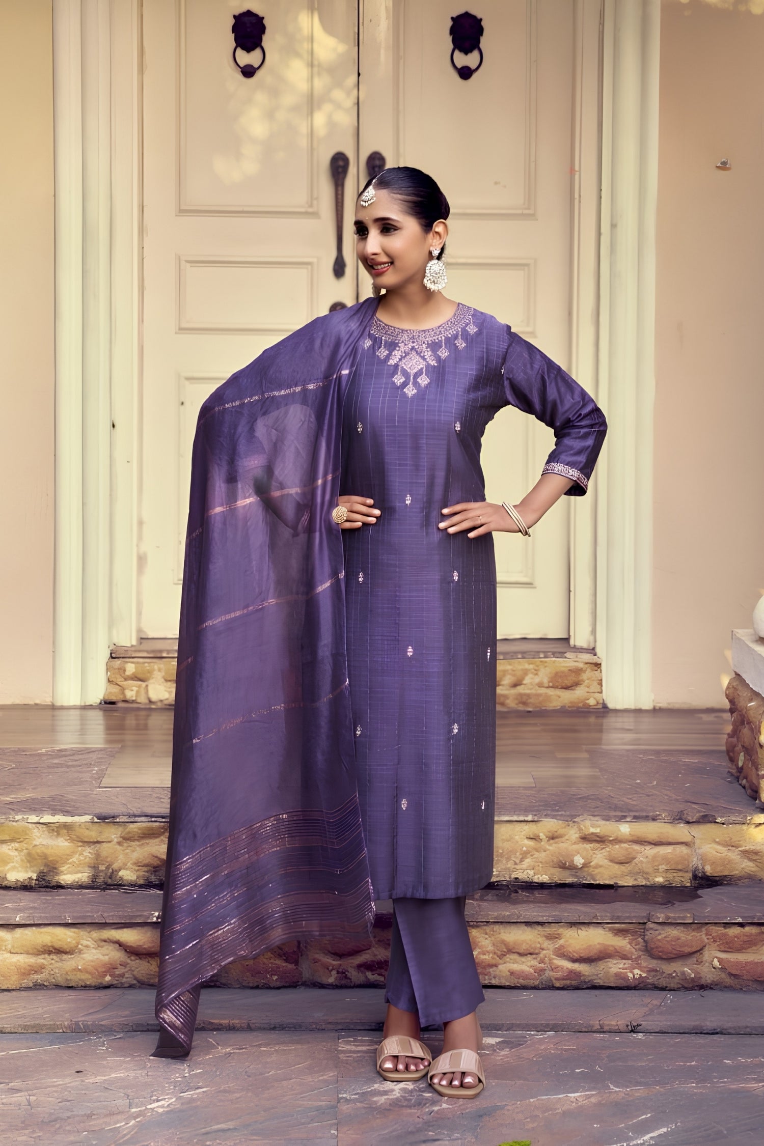 Woman in a purple traditional outfit standing on a wooden floor.