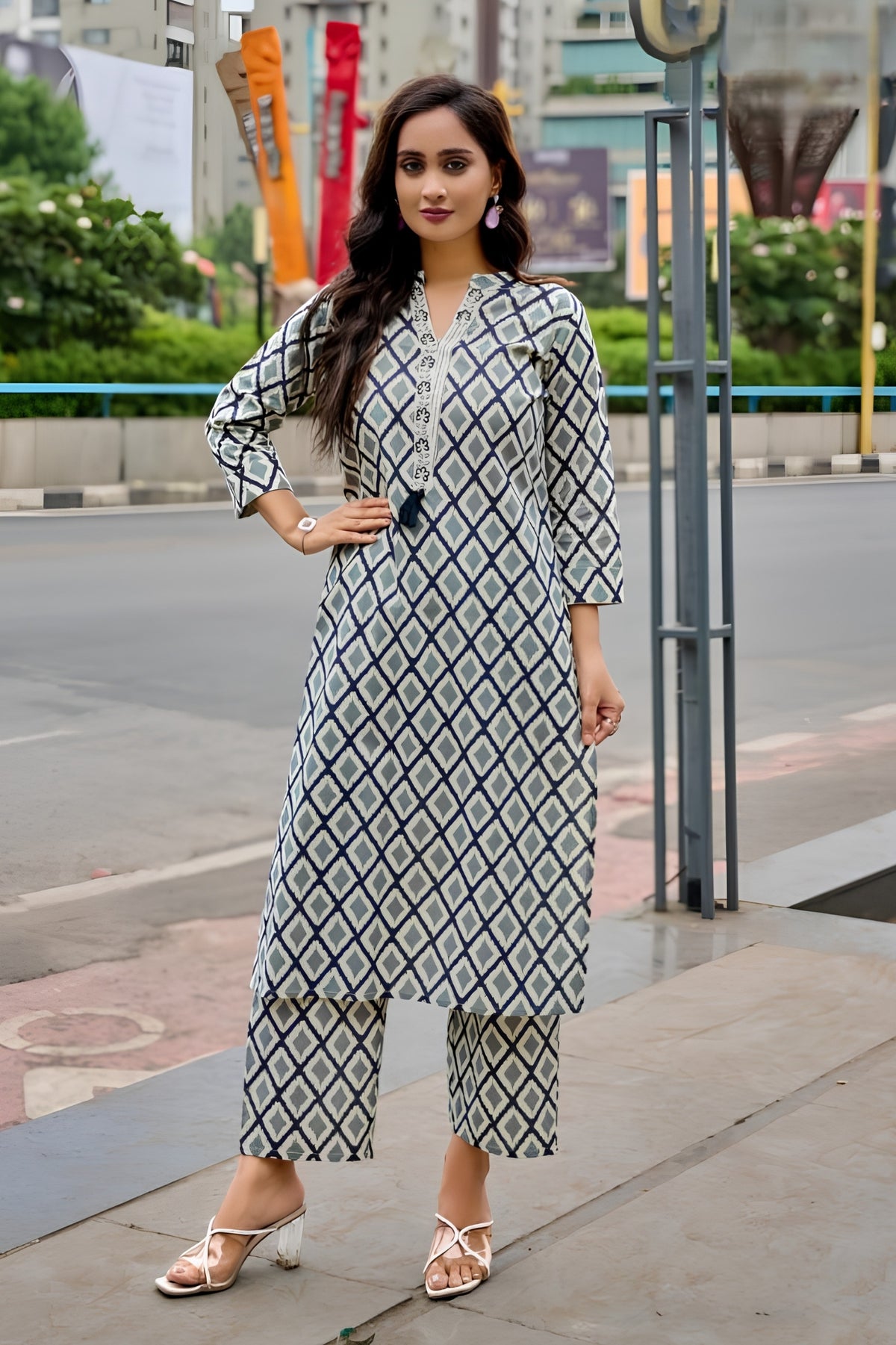 Woman in a patterned outfit standing on a city street.
