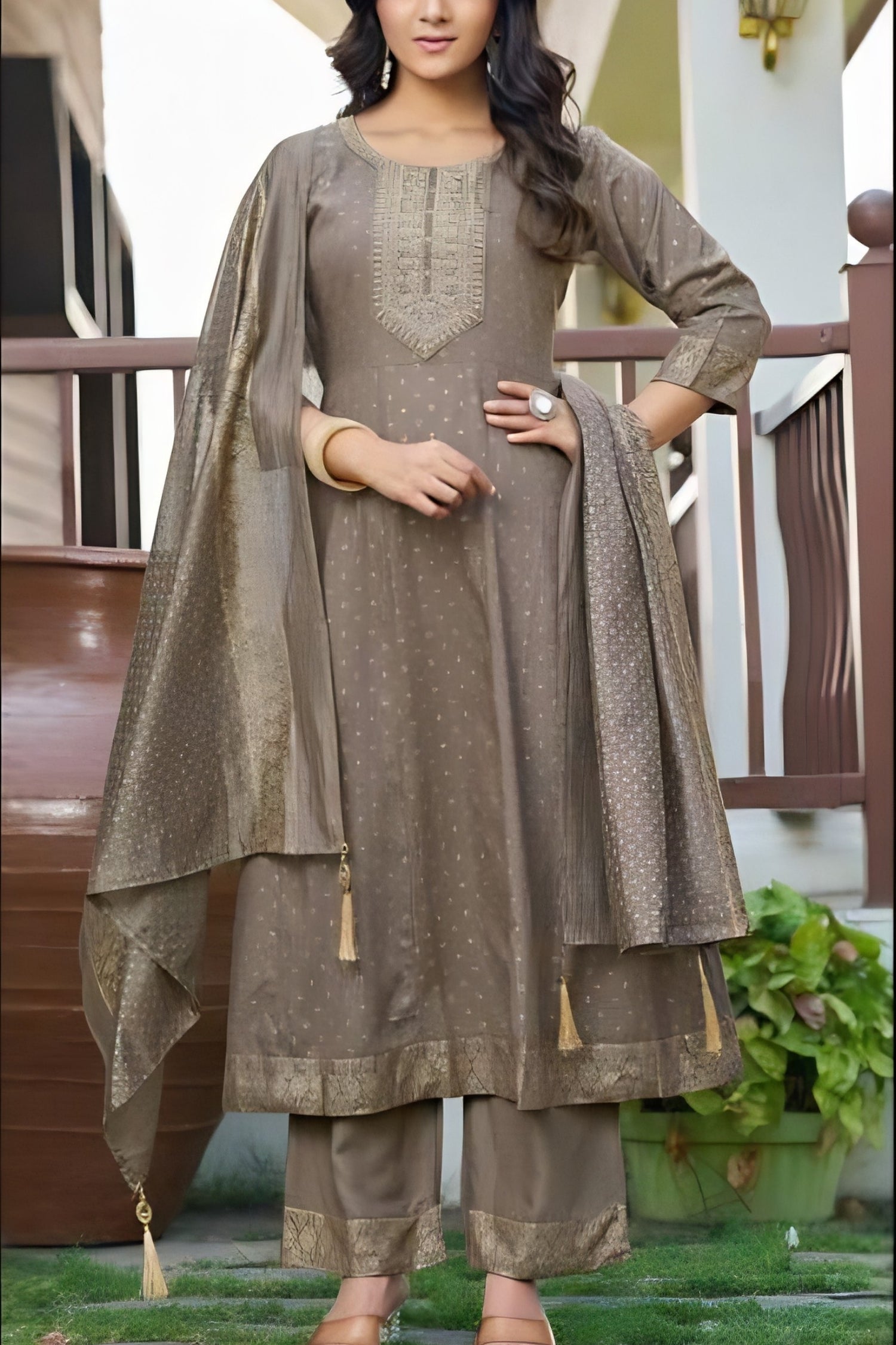 Woman wearing a brown traditional outfit with a matching dupatta on a balcony.
