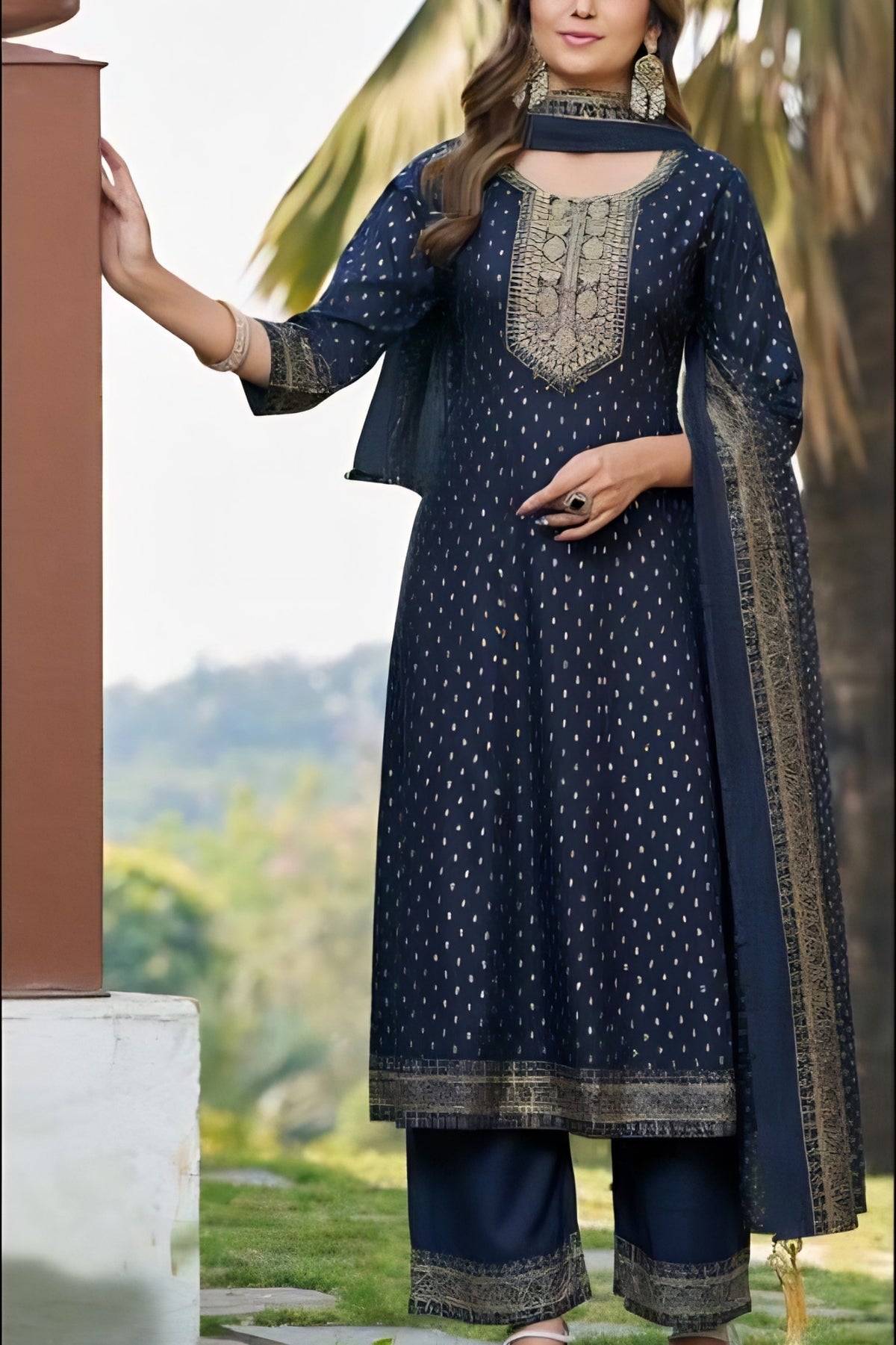 Woman wearing a navy blue traditional outfit with intricate patterns in an outdoor setting.