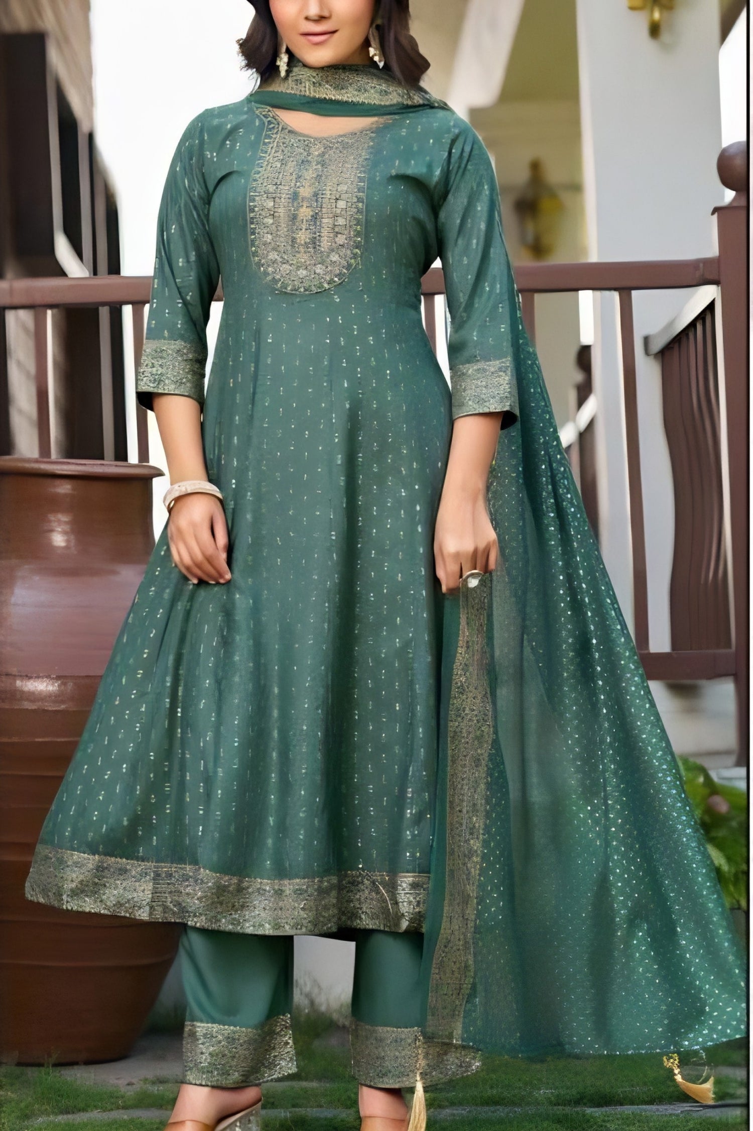 Woman wearing a green traditional outfit with matching dupatta outdoors.